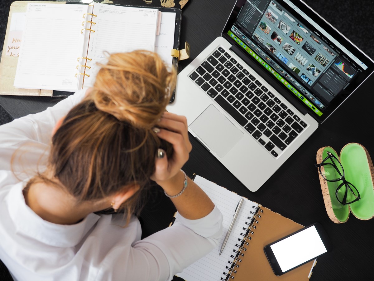 Vrouw met handen in het haar achter een laptop